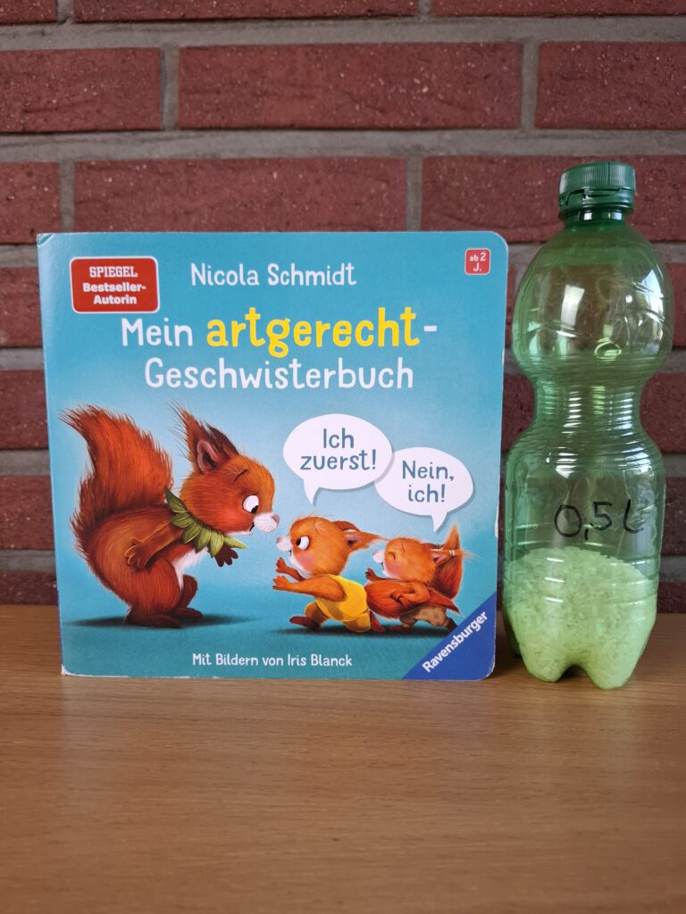 Mein artgerecht-Geschwisterbuch neben einer 0,5-Liter-Flasche
