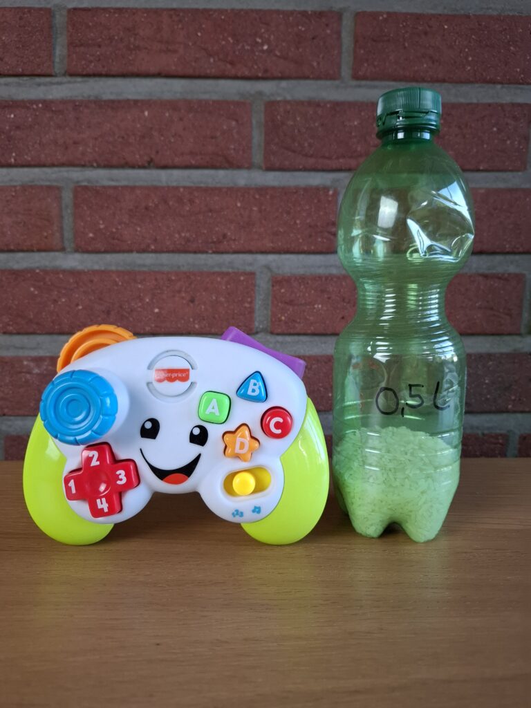 Spiel-Controller von Fisher-Price neben einer 0,5-Liter-Flasche als Größenvergleich