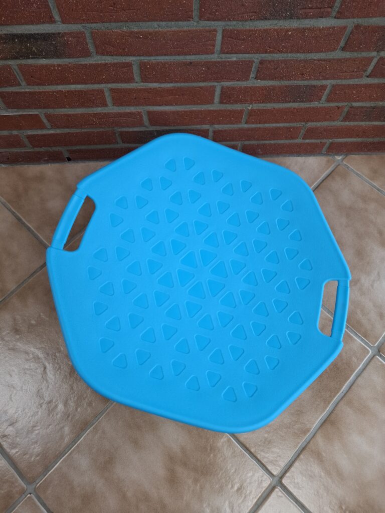 Blaue Sitzscheibe des Drehstuhls mit Dreiecksmuster und zwei Griffen